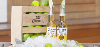 Two Coronas sitting on a table with a lime wedge in the top